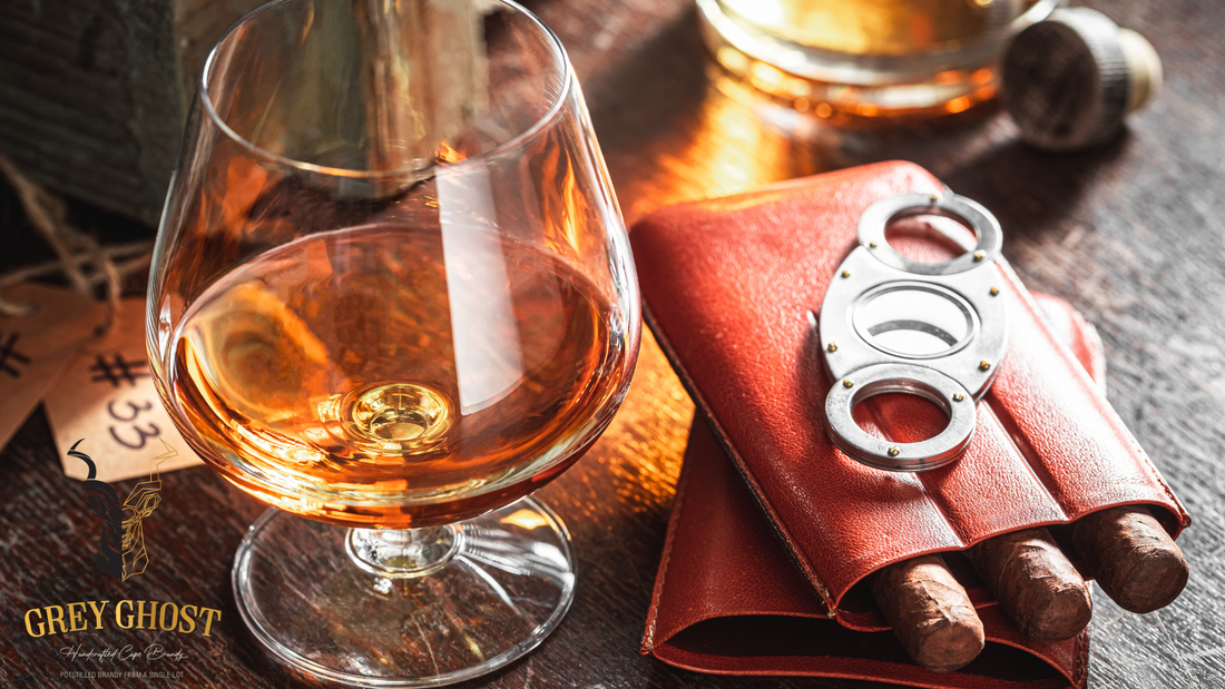 A glass of Grey Ghost Handcrafted South African brandy alongside premium cigars, showcasing the rich color and luxury of the Premium VSOP South African Brandy.